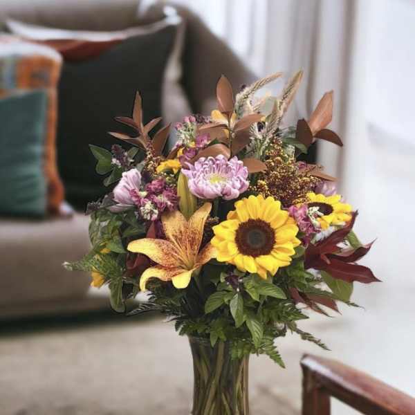 Bouquet of sunflowers, lilies, and mixed blooms in a glass vase