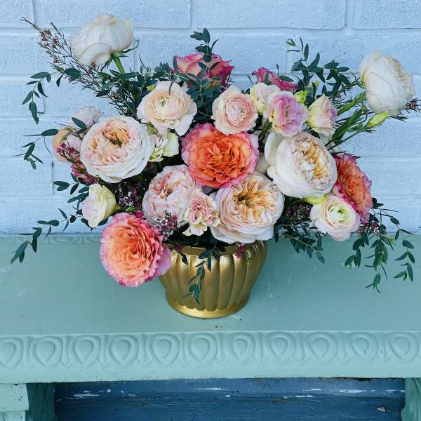 Peach and pink roses arranged in a gold vase