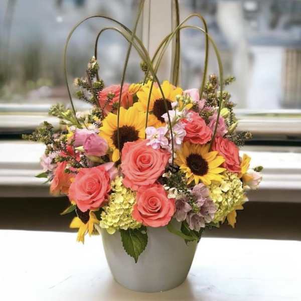 Basket arrangement of pink roses and yellow sunflowers in a gray container
