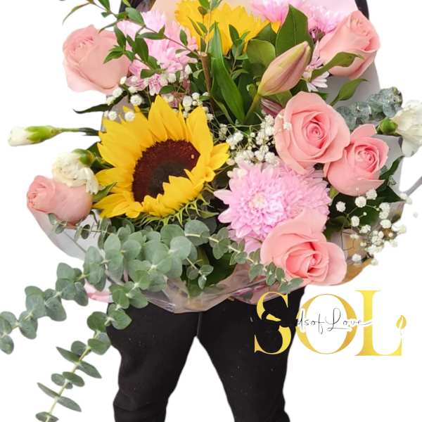 Bouquet of pink roses, a sunflower, and pink blooms with greenery