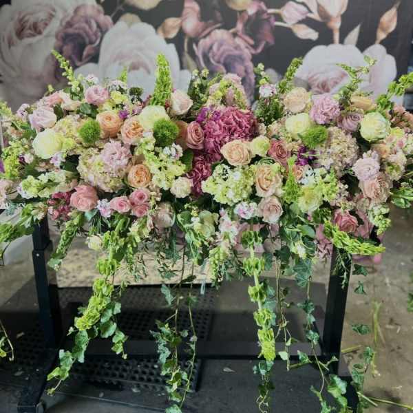 Large pastel floral arrangement with cascading greenery on a black stand