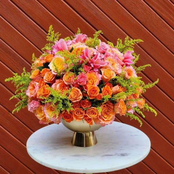 Large bouquet of orange and pink roses in a gold vase