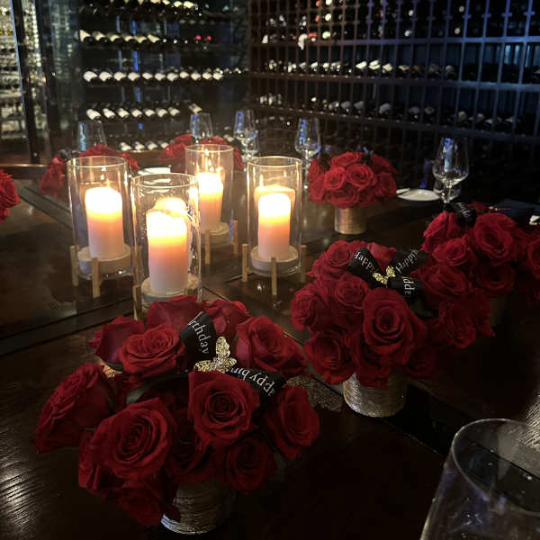 Red rose centerpieces with lit candles on a dining table