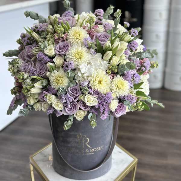 Lavender and white bouquet in a dark round hatbox