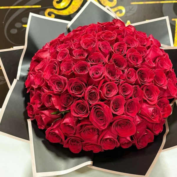 Round bouquet of red roses wrapped in black paper