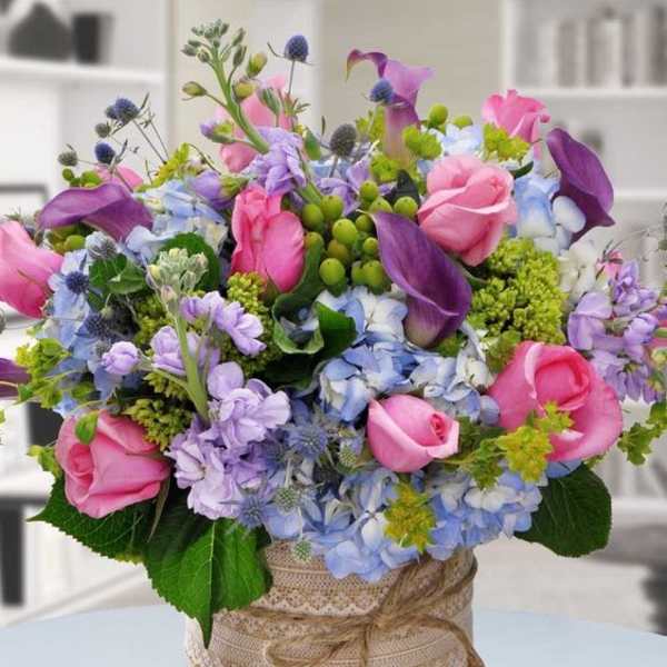 Pink roses and purple calla lilies in a glass vase with blue flowers