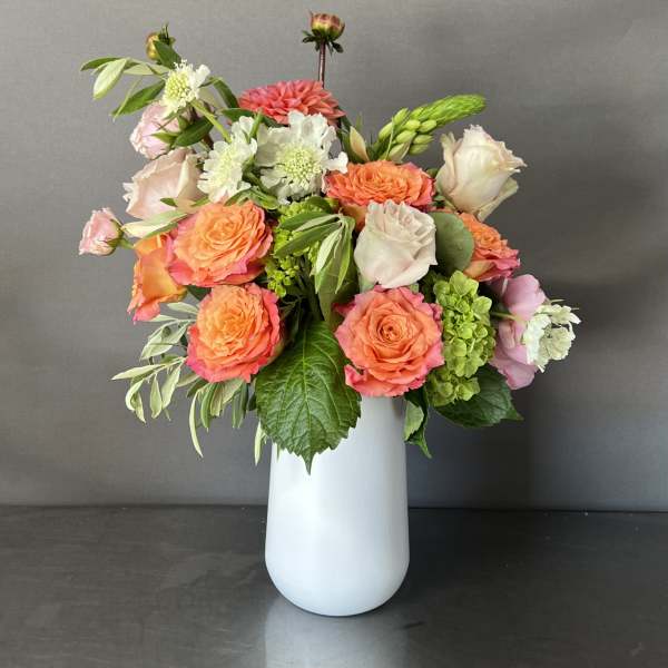 Bouquet of coral and blush roses in a white vase