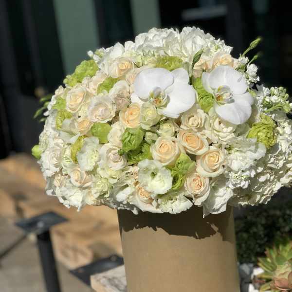 White and cream bouquet with orchids and roses in a tan box
