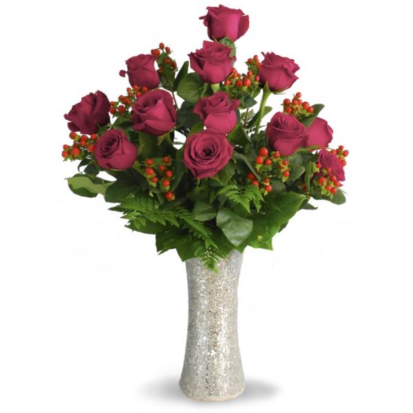 Bouquet of magenta roses with red berry accents in a glittery vase