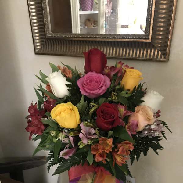 Mixed bouquet of roses and alstroemeria in a vase with a colorful ribbon