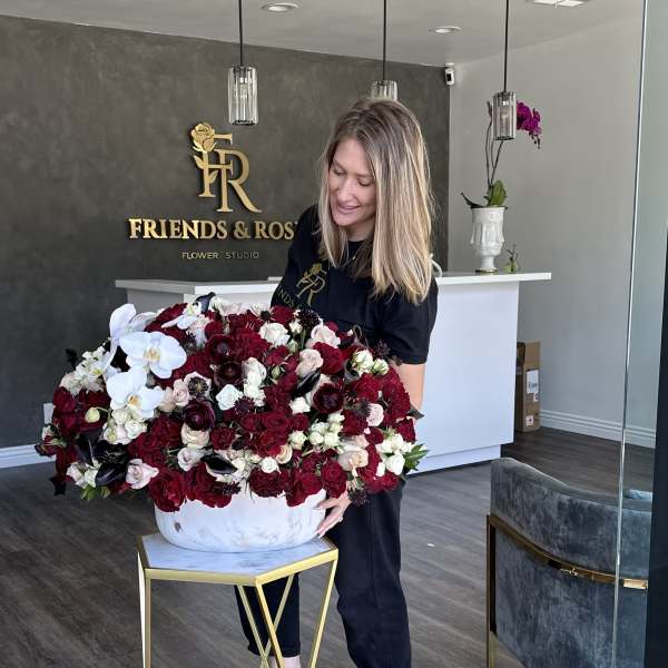 Large red and white floral arrangement in a white bowl vase