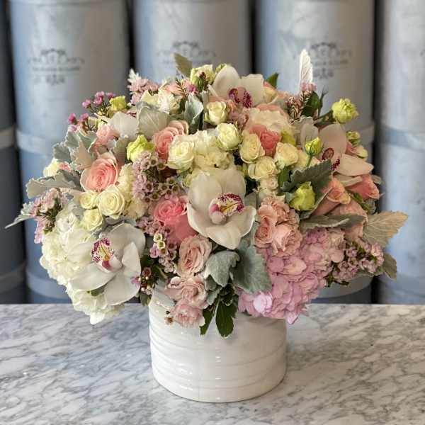 Pastel bouquet of roses, hydrangeas, and orchids in a white vase