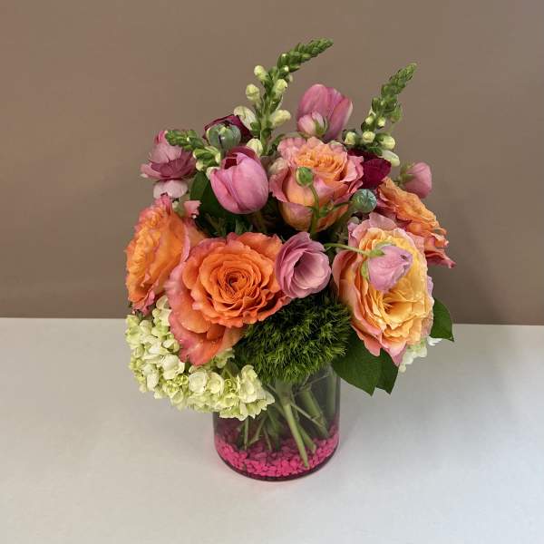 Bouquet of orange and pink roses with snapdragons in a glass vase