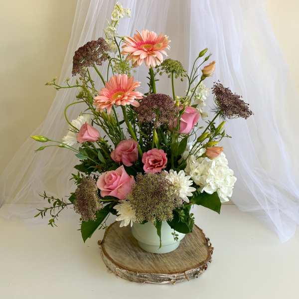 Pink roses and gerbera daisies in a white vase