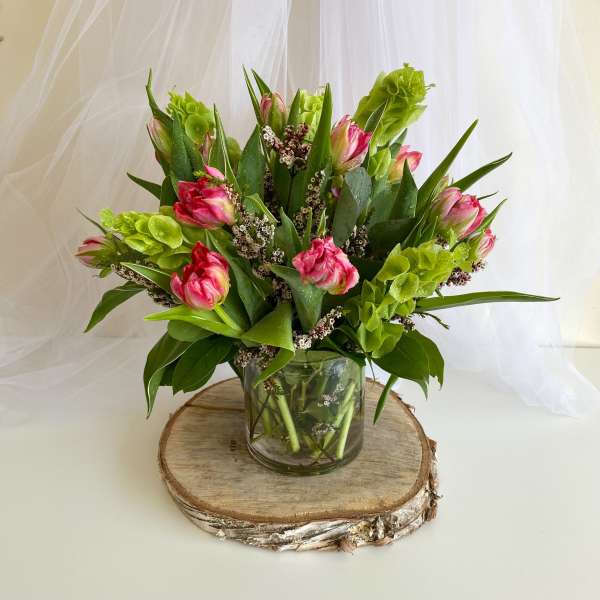 Pink and green tulips arranged in a clear glass vase