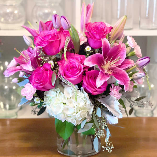 Pink roses and lilies arranged with white hydrangea in a glass vase