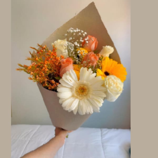 Bouquet of white and peach flowers wrapped in brown paper