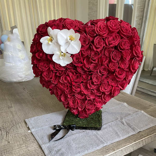 Heart-shaped arrangement of red roses with white orchids