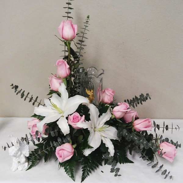 Pink roses and white lilies arranged with eucalyptus in a clear vase