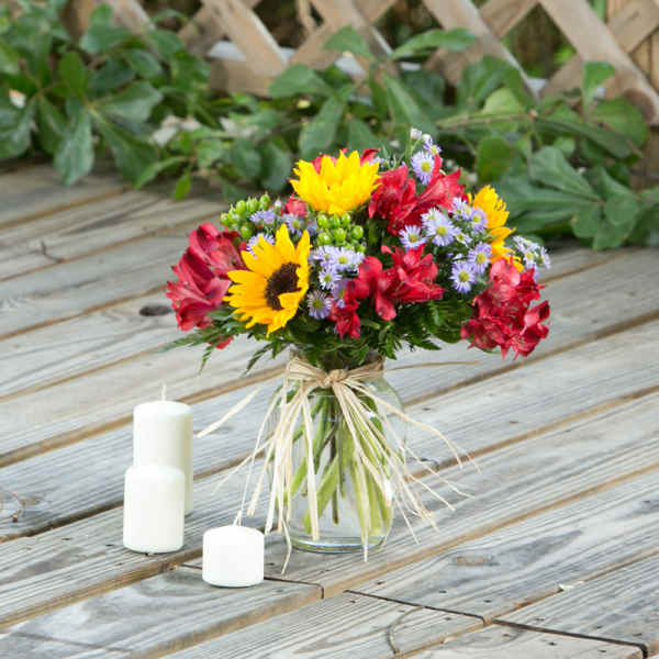 Bouquet of sunflowers and red alstroemeria in a glass vase