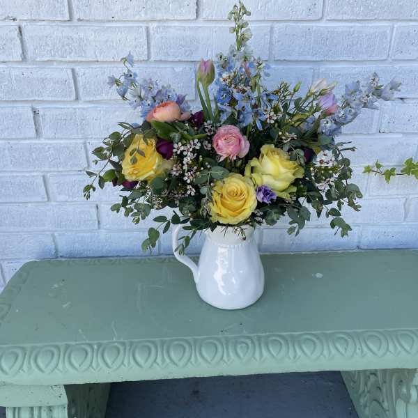 Mixed bouquet in a white pitcher vase with yellow and pink blooms