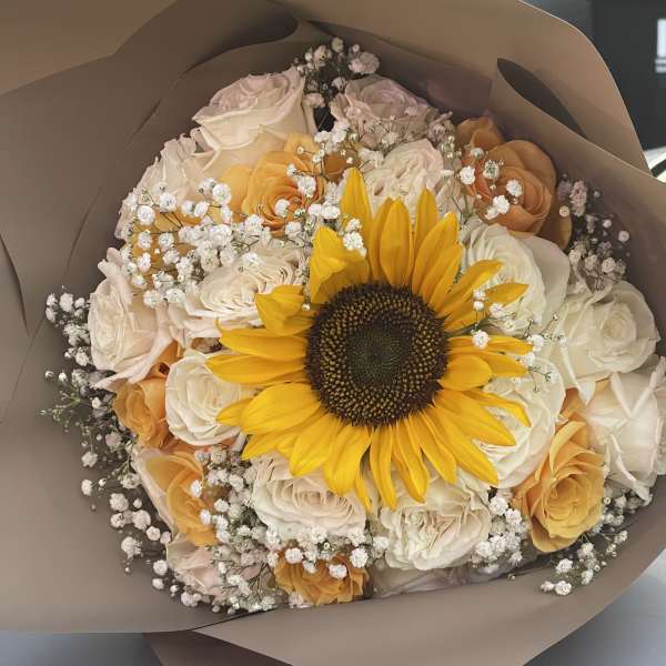 Bouquet of yellow sunflower and pale roses wrapped in brown paper