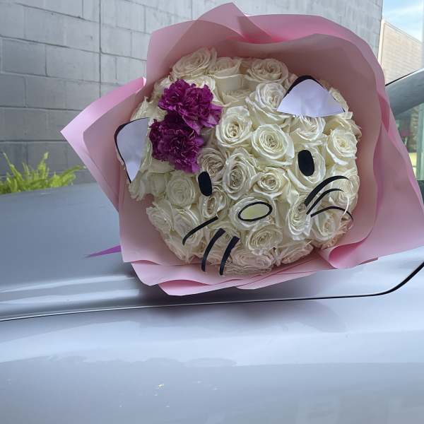 Bouquet of white roses with pink wrapping and a cat face design