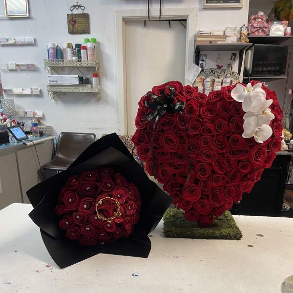 Heart-shaped red rose arrangement with white orchids and a black-wrapped rose bouquet