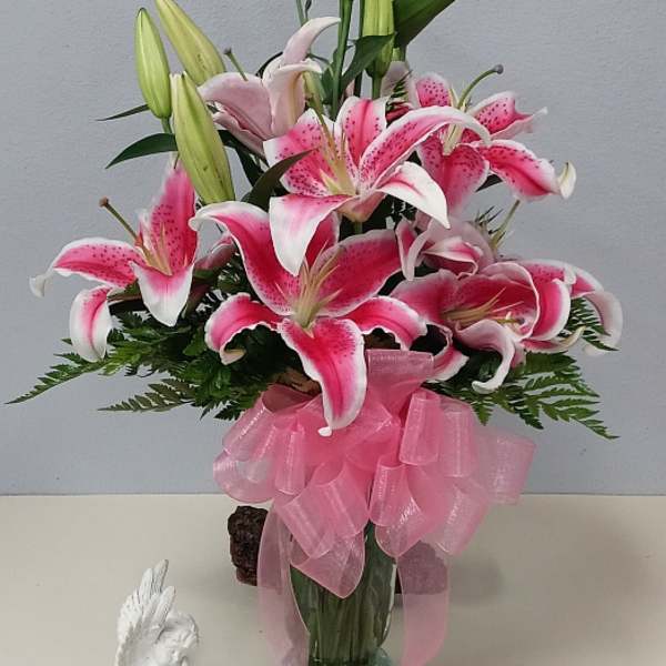 Pink stargazer lilies in a glass vase with a pink ribbon bow