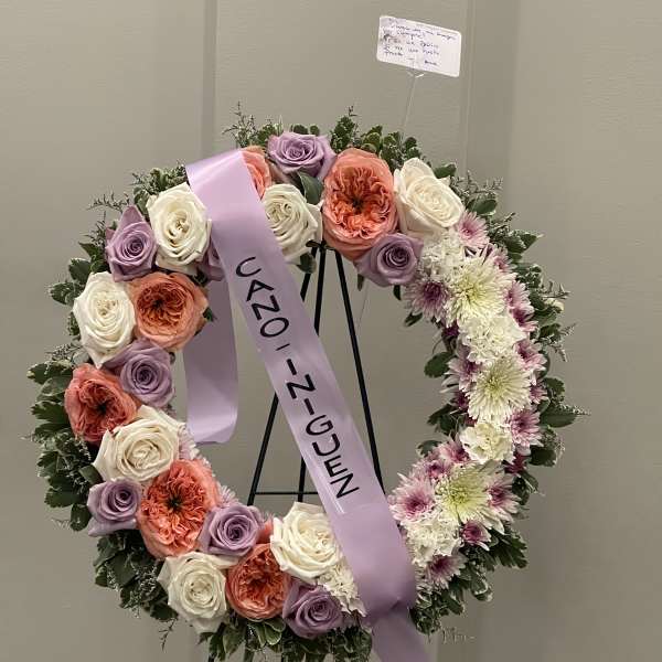 Circular floral wreath on an easel with pastel roses and mums