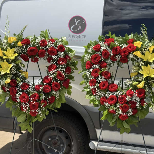 Two red rose wreaths with yellow lilies on black stands