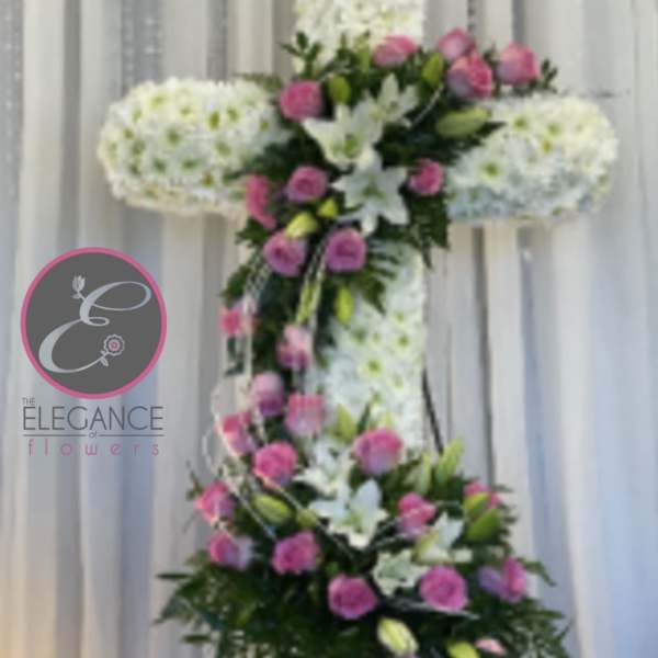Tall floral cross on a stand with white and pink flowers