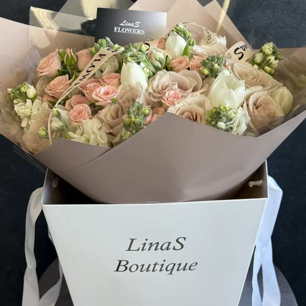 Bouquet of blush and cream roses with white blooms in a gift box