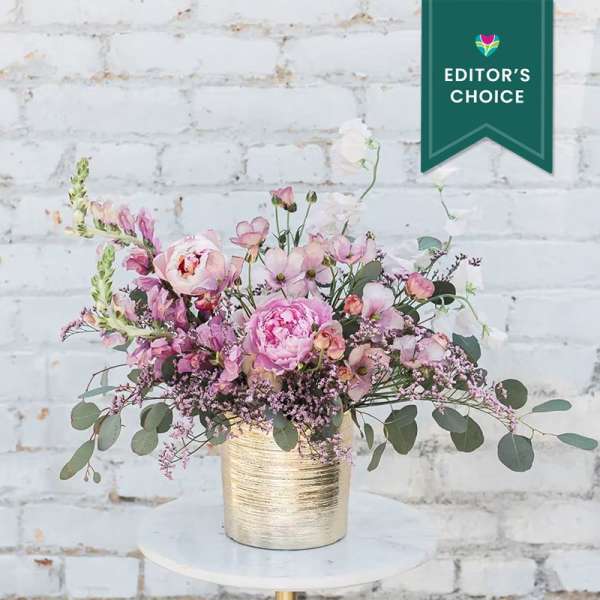 Pink and white floral arrangement in a gold vase