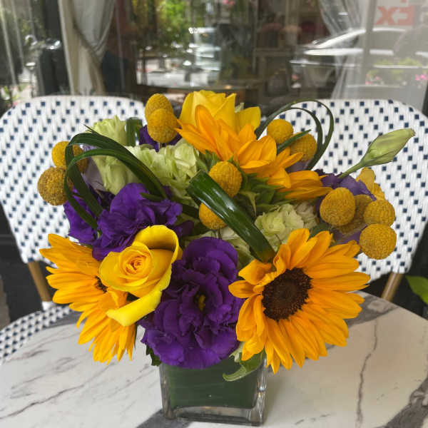 Bouquet of yellow and purple flowers in a clear glass vase