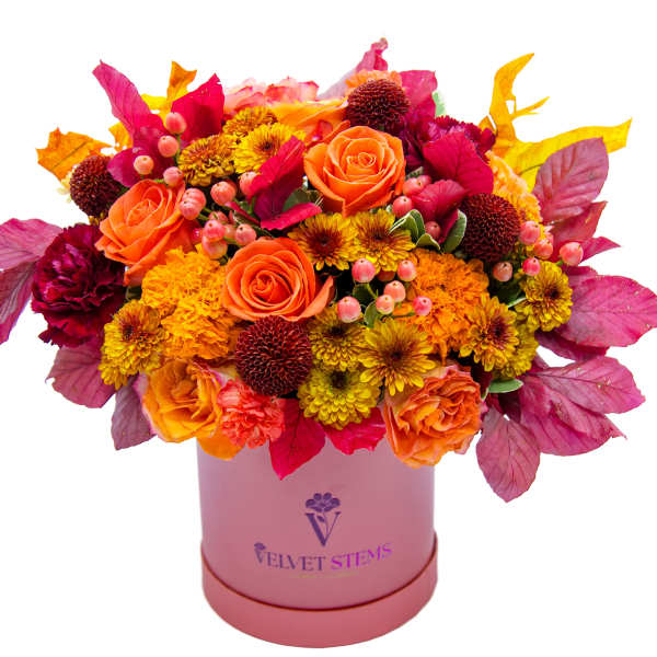 Orange and yellow mixed bouquet in a pink hatbox with magenta foliage