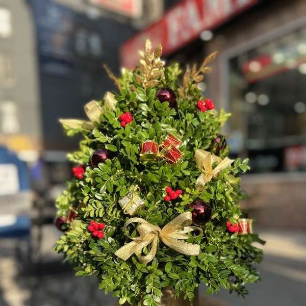 Small decorated evergreen topiary in a gold pot with ribbon and ornaments