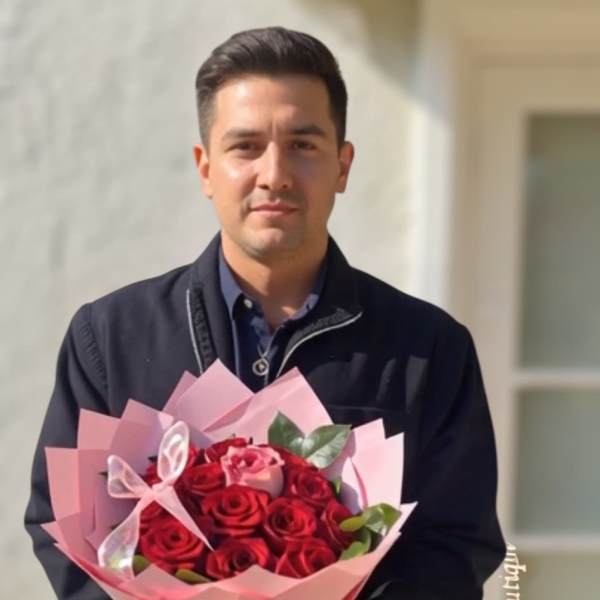 Man holding a bouquet of red roses wrapped in pink paper