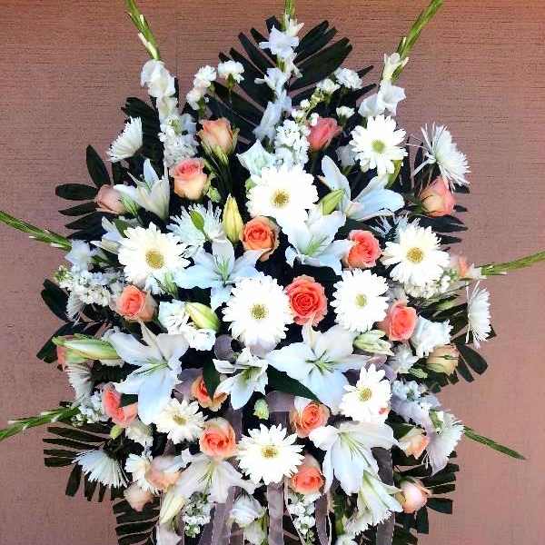 Standing floral spray with white lilies, daisies, and peach roses
