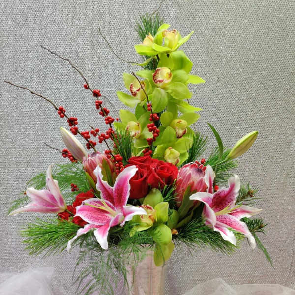 Tall floral arrangement with orchids, roses, and lilies in a gold vase