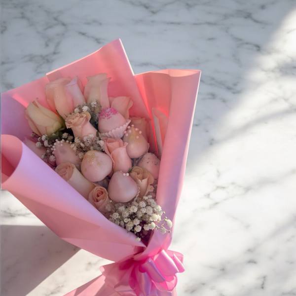 Pink bouquet of roses with small white filler flowers in pink wrapping