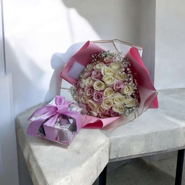 Bouquet of pink and white roses with a small gift box