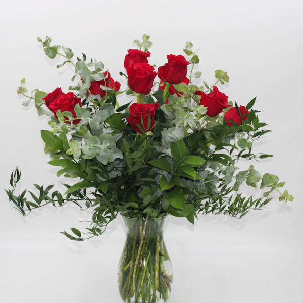 Red roses in a clear glass vase with airy greenery