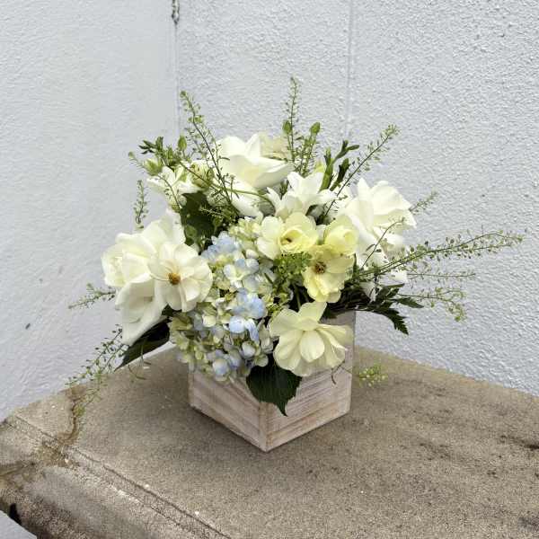 White and pale yellow flowers arranged in a wooden box