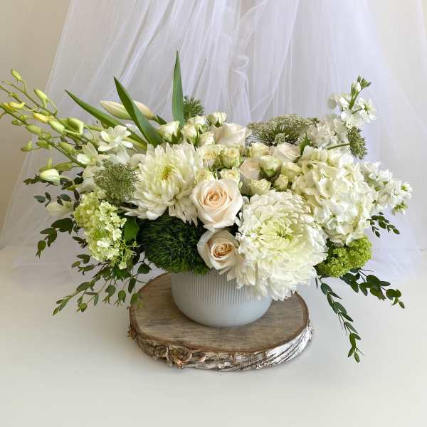 White floral arrangement in a round vase with roses and chrysanthemums
