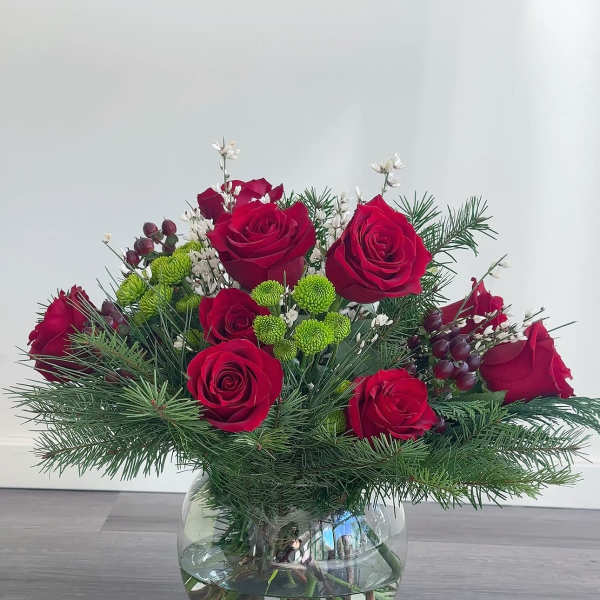 Red roses in a glass vase with pine and small white accents