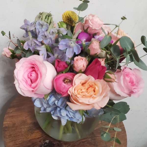 Bouquet of pink and peach roses with blue hydrangeas in a glass vase
