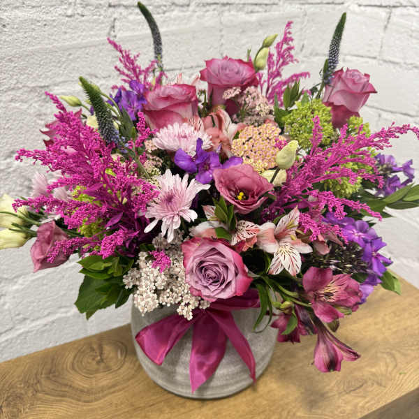 Pink and purple mixed bouquet in a gray vase with a satin ribbon