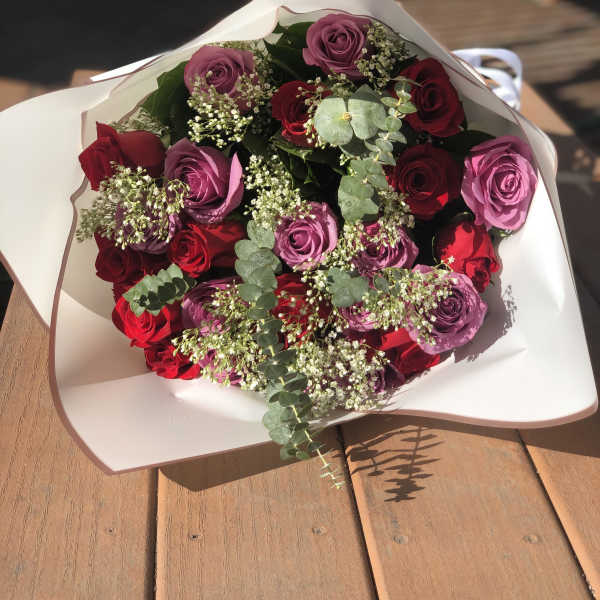 Bouquet of red and purple roses wrapped in white paper