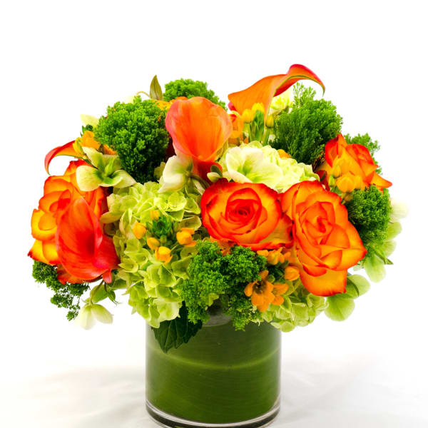 Orange roses and calla lilies in a green glass vase